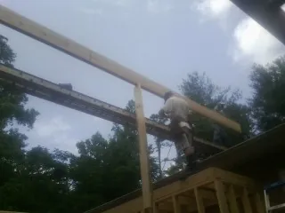 Carpenter setting a ridge beam over a new addition frame — Ice Dam Removal by Roofing Brothers in Philpot