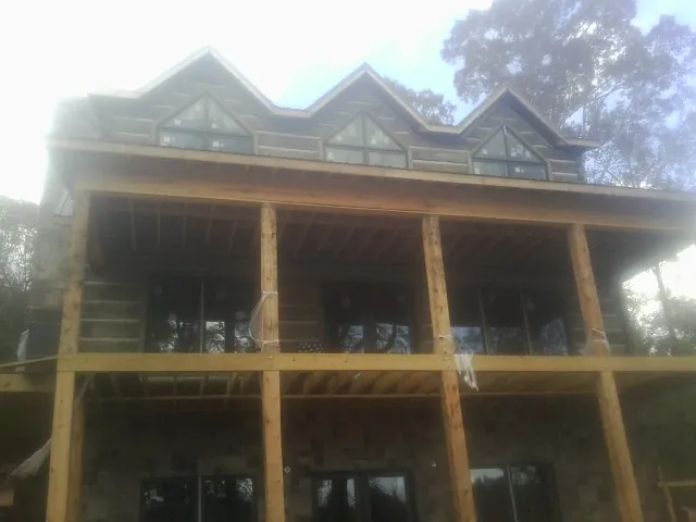 Dormers and porch framing on a large log home under construction — Roof Coating work by our crew in Philpot