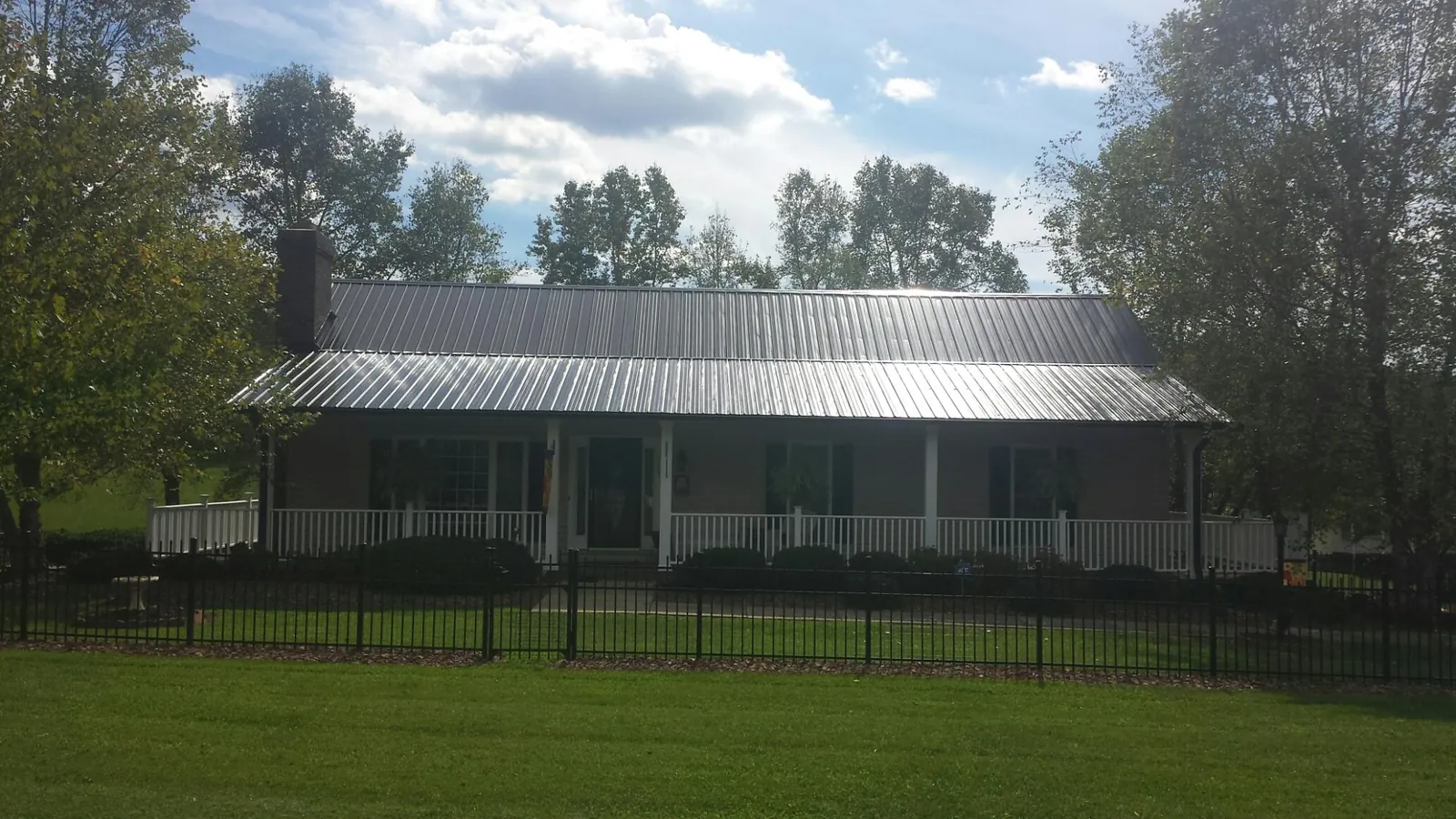 Gray metal roof on a brick ranch with a full width front porch — Gutter Guard Installation work by our crew in Philpot