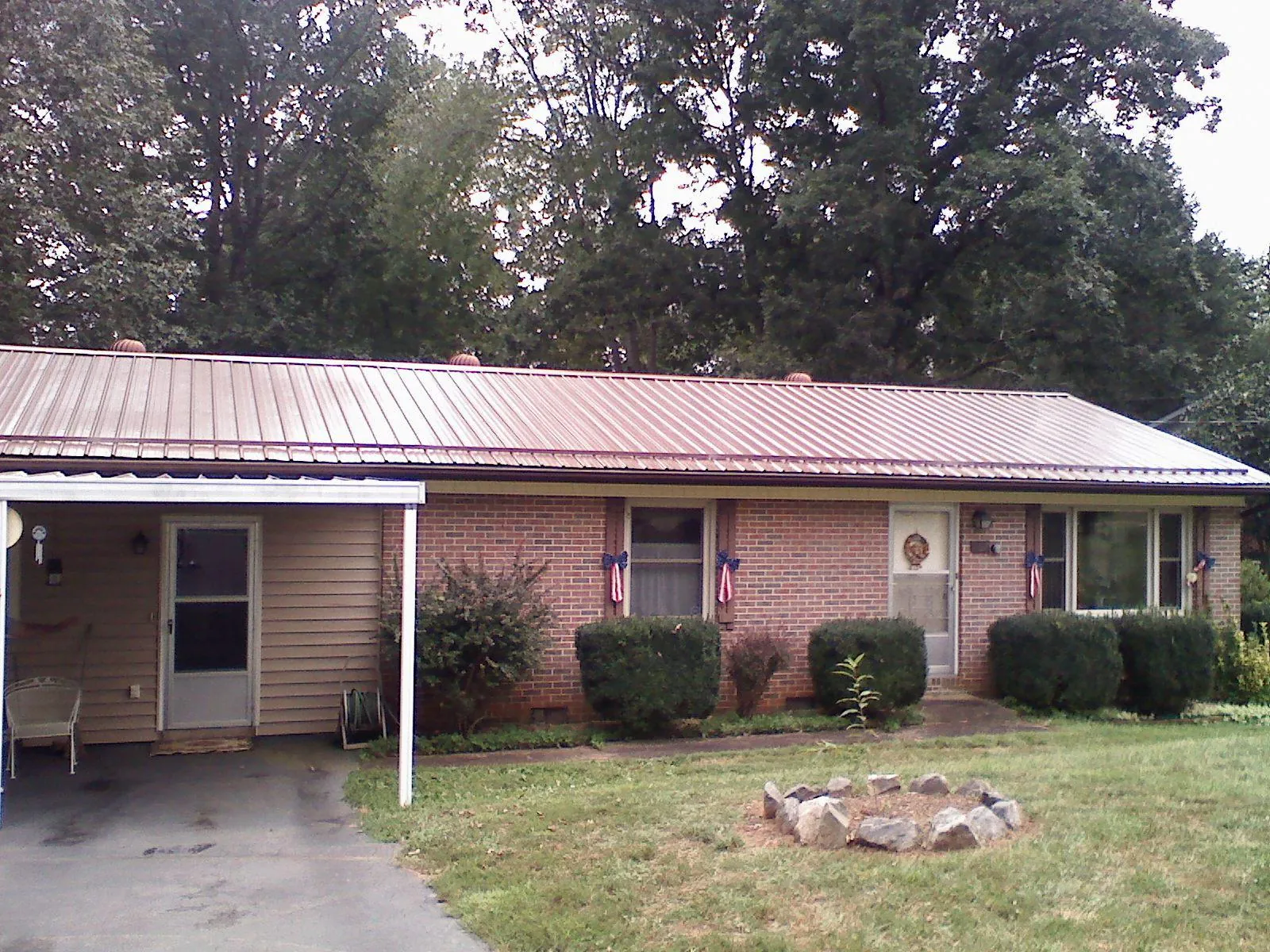 Bronze metal roof and carport on a brick ranch home — Roof Repair work by our crew in Philpot