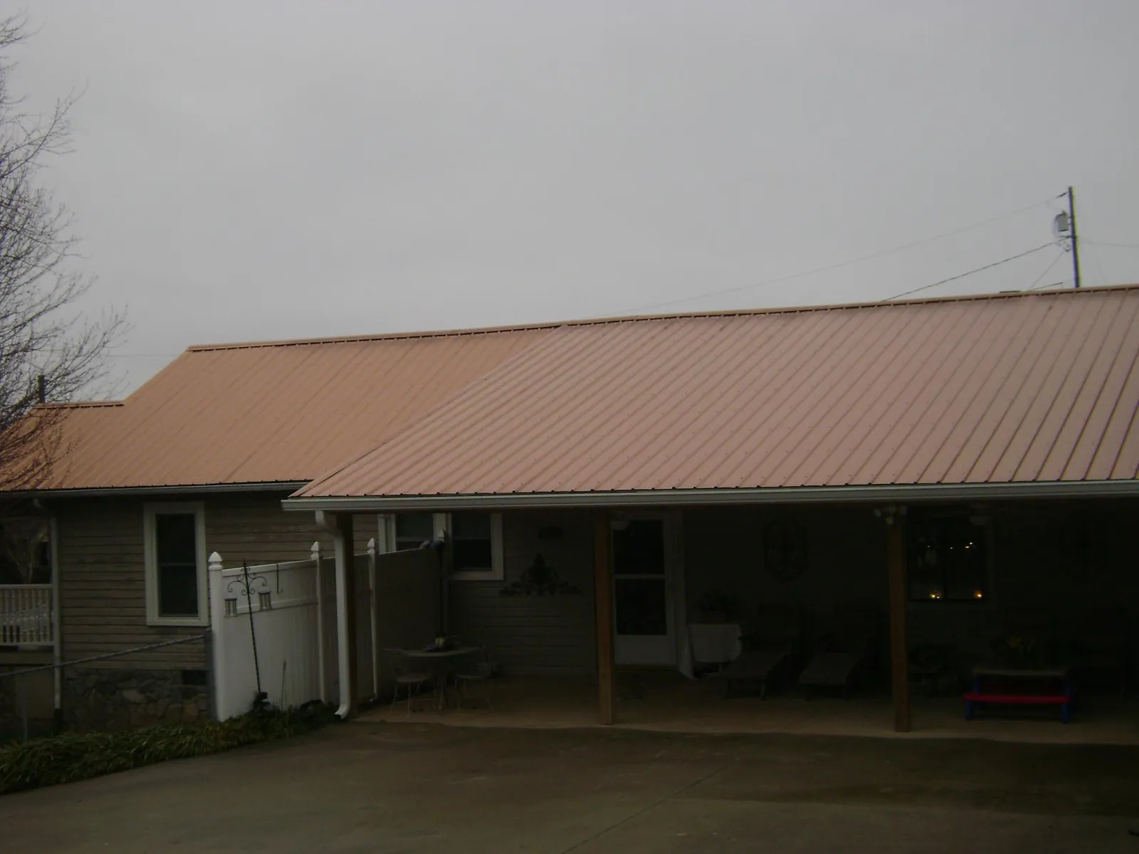 Copper toned metal roof over a wide covered patio in Philpot