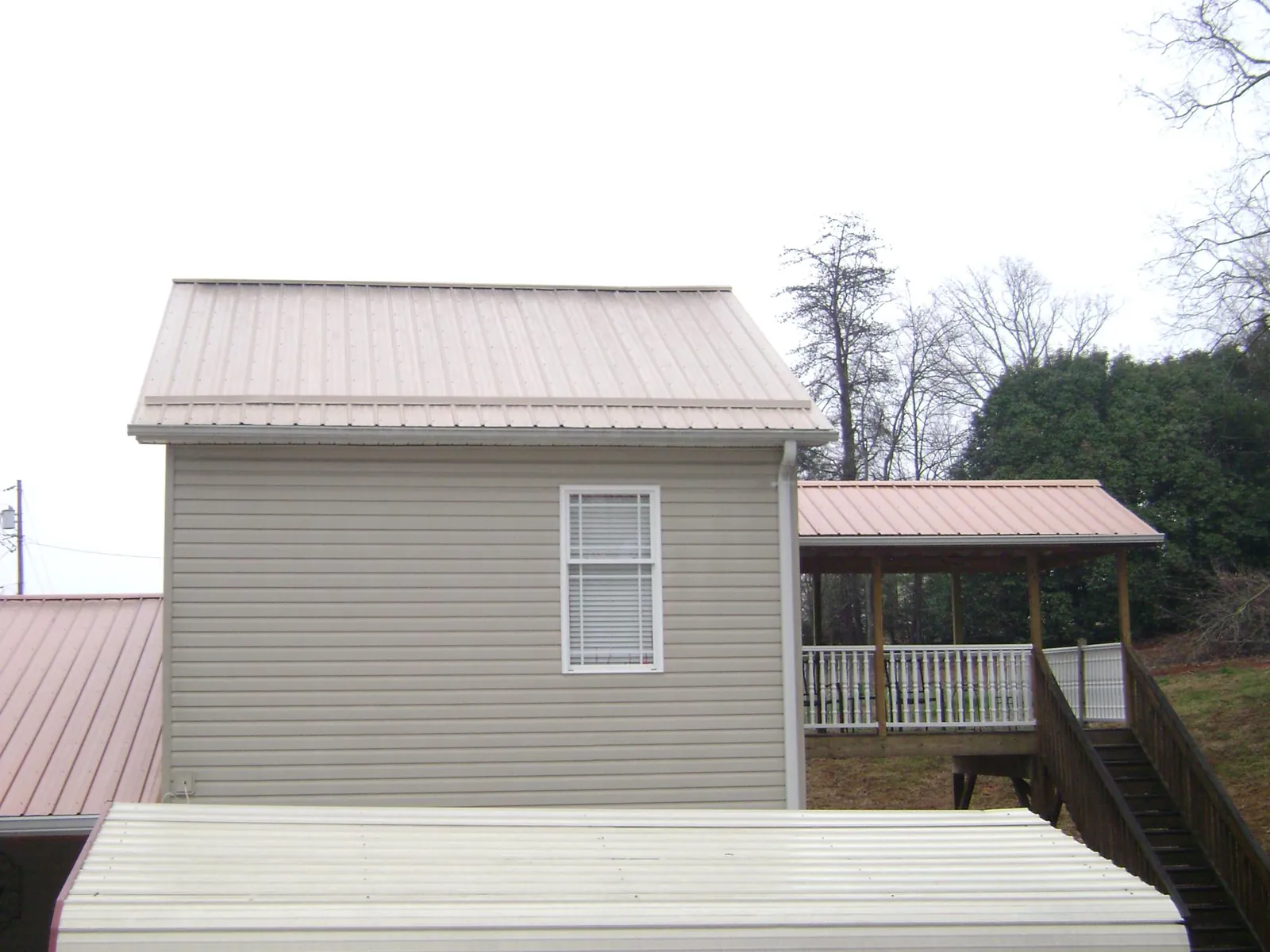 Tan metal roofs on a two story addition and attached porch, from a Roof Replacement job in Philpot