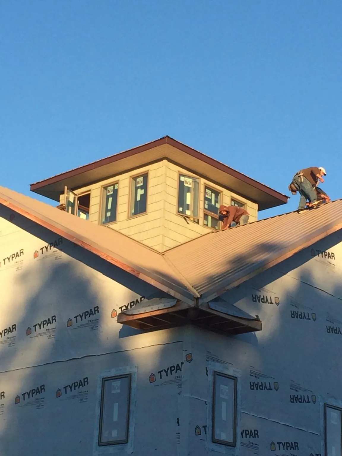 Roofers working around a rooftop cupola on a new metal roof at sunset — Roof Waterproofing in Philpot by Roofing Brothers